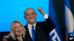 Former Israeli Prime Minister and the head of Likud party Benjamin Netanyahu and his wife, Sara, celebrate after first exit poll results for the Israeli Parliamentary election at his party's headquarters in Jerusalem, Nov. 2, 2022.