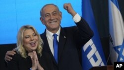 El exprimer ministro de Israel y candidato del partido Likud, Benjamin Netanyahu, y su esposa Sara, gesticulan tras conocerse los resultados de las primeras encuestas de salida de las elecciones parlamentarias, en Jerusalén, el 2 de noviembre de 2022. (AP Foto/Tsafrir Abayov)