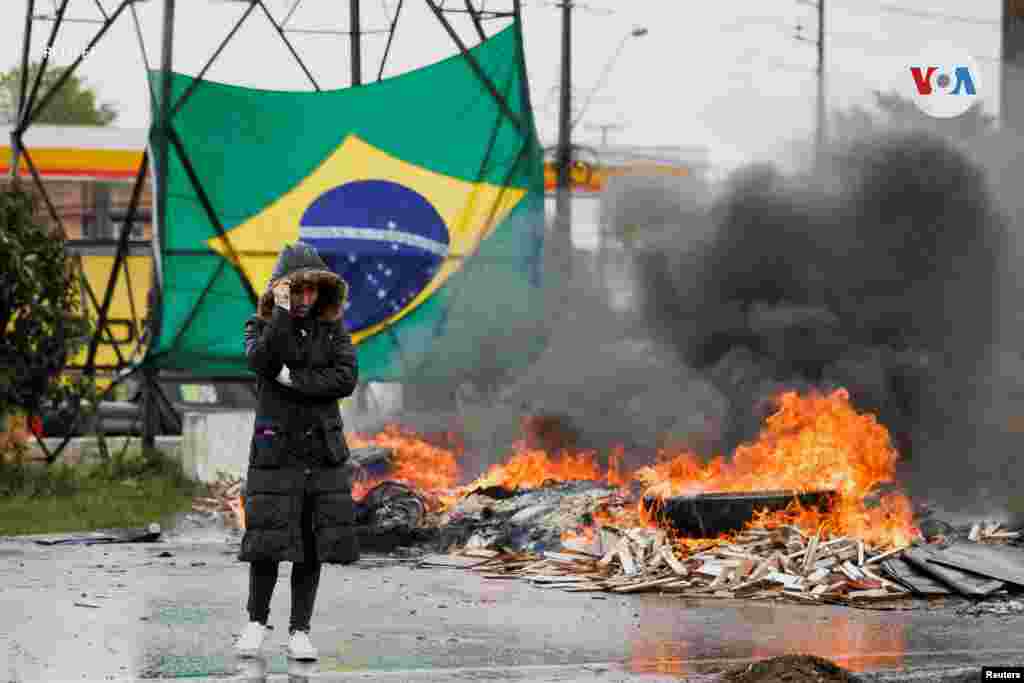 Una persona en una carretera junto a un neumático en llamas mientras partidarios del presidente de Brasil Jair Bolsonaro bloquean una carretera durante una protesta por la victoria de Lula de Silva en la segunda vuelta de las elecciones presidenciales, en Curitiba, en el estado de Paraná, Brasil, el 1 de noviembre de 2022.&nbsp;