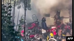 This image grab from a UGC video posted on Nov. 1, 2022, reportedly shows security forces trying to enter a closed shopping center on Amir Kabir street in Iran's capital Tehran before being engulfed by gas matter. (UGC via AFP)