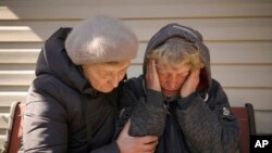 A neighbor comforts Natalia Vlasenko, whose husband, Pavlo Vlasenko, and grandson, Dmytro Chaplyhin, called Dima, were killed by Russian forces, as she cries in her garden in Bucha, Ukraine, April 4, 2022.