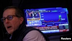 Сотрудник Нью-Йоркской фондовой биржи слушает выступление председателя ФРС Джерома Пауэлла, 2 ноября 2022 года