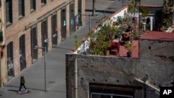 Seorang pria bermain gitar di atap rumahnya di tengah pandemi COVID-19 di Barcelona, Spanyol, 5 April 2020. (AP/Emilio Morenatti)