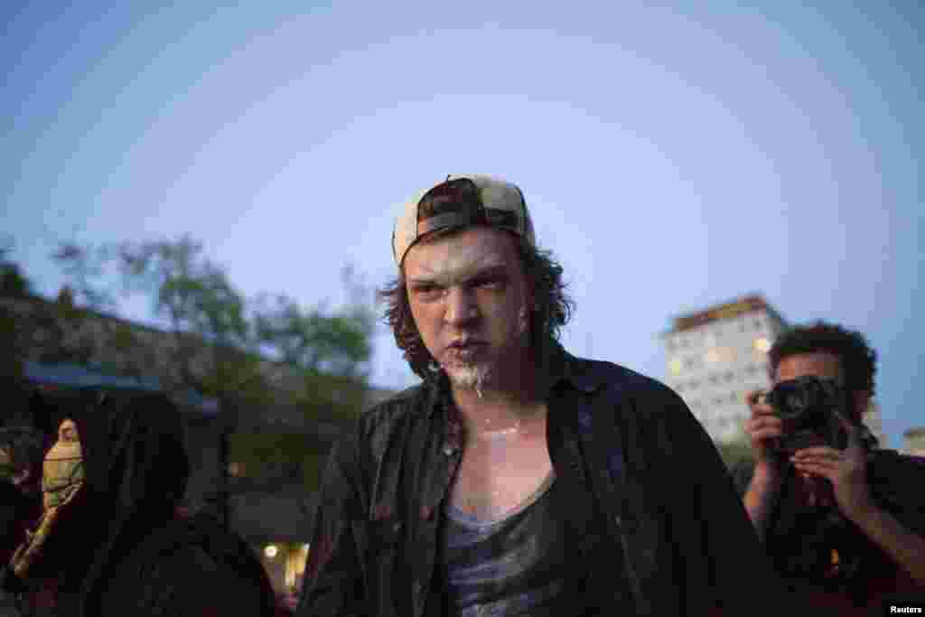 Seorang pengunjuk rasa bereaksi setelah mendapat semprotan merica dan kemudian diobati dengan cairan seperti susu dalam demonstrasi anti-kapitalis di Seattle, Washington, 1 April 2014. &nbsp;
