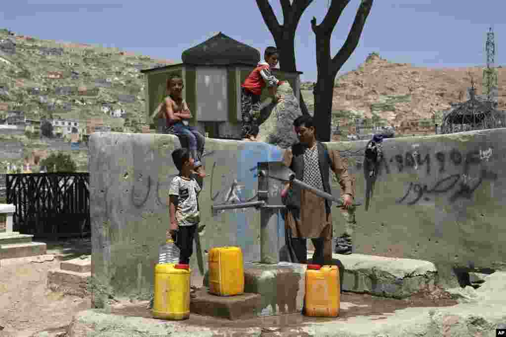 A man and his children collect water from a public water pump in Kabul, Afghanistan.