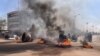Commuters ride their motorcycles through burning barricades in central in Ouagadougou where group of demonstrators supporting the army protested against President Marc Christian Kabore, in Ouagadougou, Burkina Faso, Jan. 23, 2022.