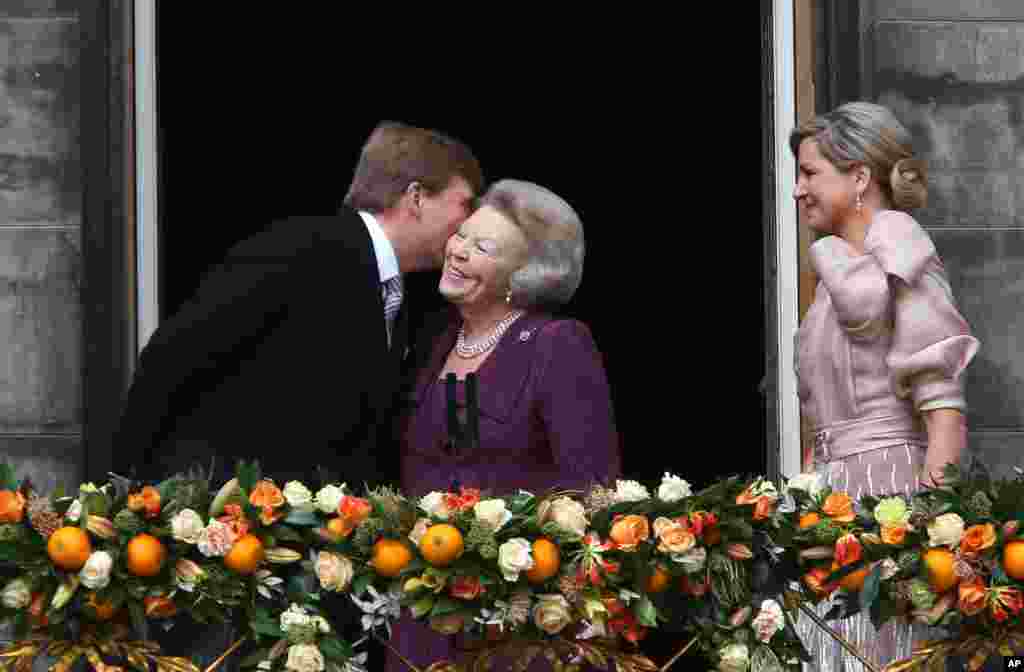 Dutch King Willem-Alexander kisses his mother Princess Beatrix as Queen Maxima looks on from the balcony of the Royal Palace in Amsterdam. 