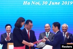 FILE - European Commissioner for Trade Cecilia Malmstrom, Romania's Business, Trade and Enterpreneurship Stefan Radu Oprea and Vietnam's Industry and Trade Minister Tran Tuan Anh attend the signing ceremony of EVFTA in Hanoi, June 30, 2019.