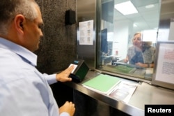 FILE - A man has his fingerprints taken electronically while taking part in a visa application demonstration at the consular section of the Embassy of the United States in Lima, Peru, October 3, 2014.