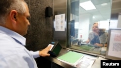 FILE - A man has his fingerprints electronically taken while taking part in a visa application demonstration.
