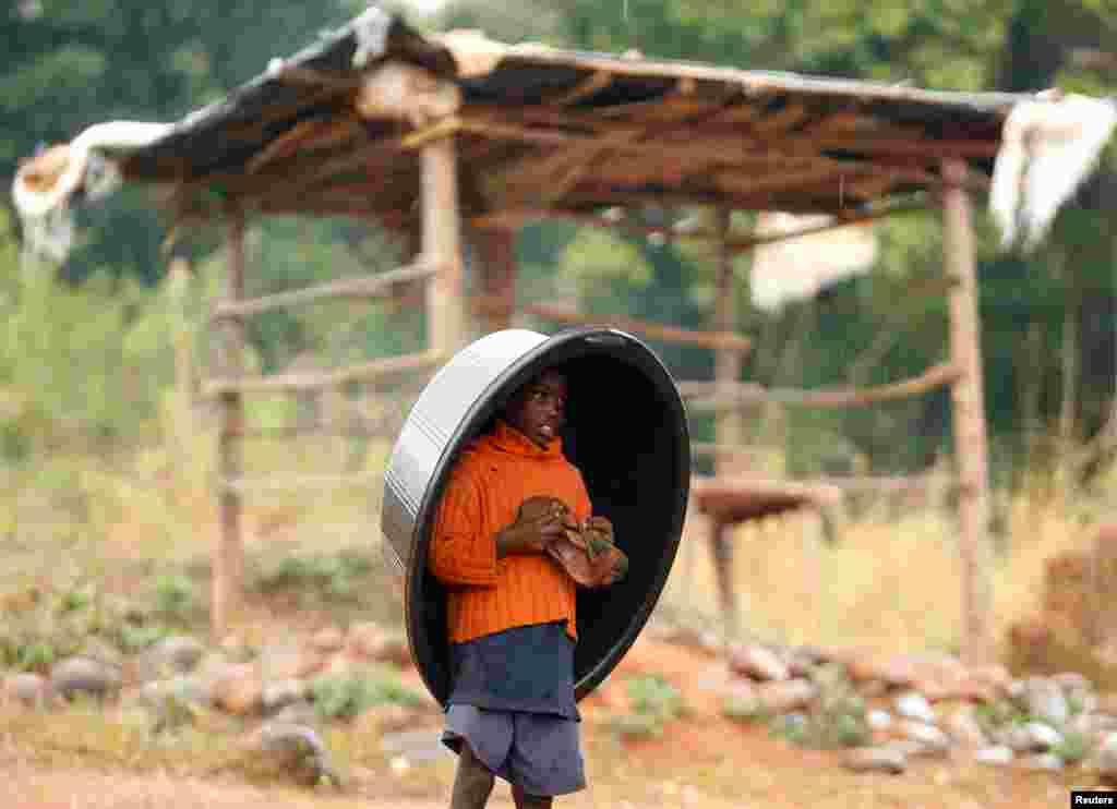 Yomg&#39;irda boshiga tog&#39;orani pana qilgan bolakay. Zimbabve.