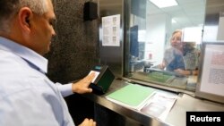 FILE PHOTO - A man has his fingerprints electronically taken while taking part in a visa application demonstration during a media tour at the consular section of the Embassy of the United States.