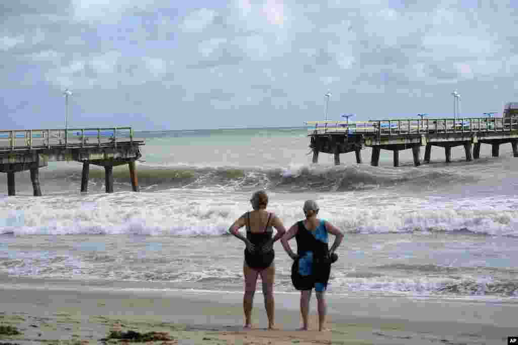 Los bañistas curiosos se paran frente a parte del muelle de pesca de Anglin, que se derrumbó después de la llegada del huracán Nicole, en Lauderdale-by-the-Sea, Florida.&nbsp;