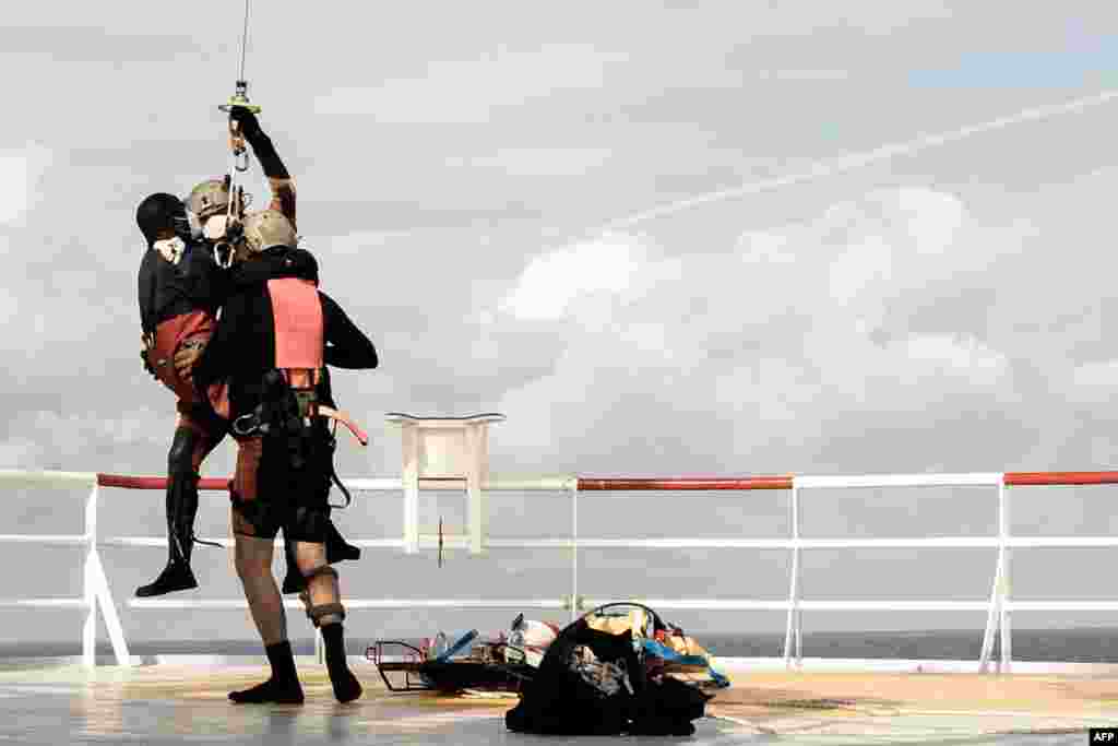 A migrant in need of urgent medical care (L) is readied to be winched up by a helicopter of the French Army from the Ocean Viking rescue ship in the Tyrrhenian Sea between Italy and Corsica island.