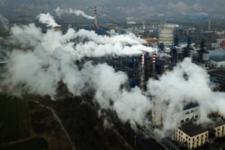 FILE - Smoke and steam rise from a coal processing plant that produces carbon black, an ingredient in steel manufacturing, in Hejin in central China's Shanxi Province, Nov. 28, 2019.