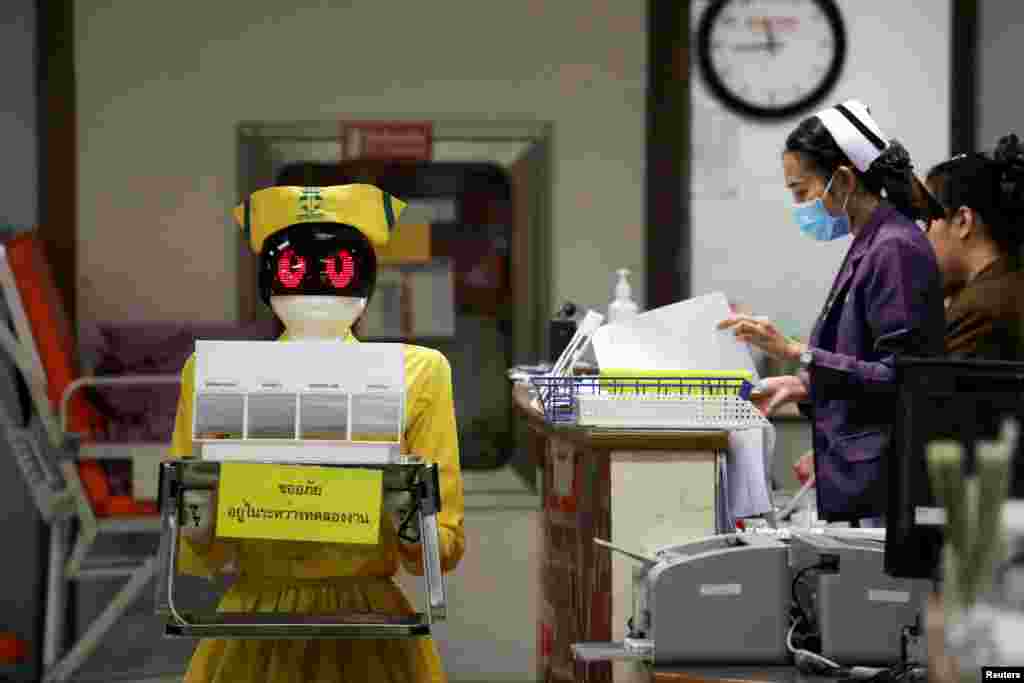 A robot wearing a nurse costume carries medical documents at Mongkutwattana General Hospital in Bangkok, Thailand.