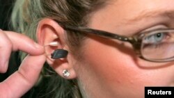 A girl puts the smallest hearing device ever built, according to the maker, into her ear after a presentation in Vienna December 11, 2008. The hearing device named "be by ReSound" built by Danish company GN weighs 1.1 grams and is 15.5 by 8.8 by 5.3 milli