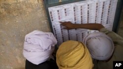 Quelques électeurs cherchent leurs noms sur une liste à l'extérieur d'un bureau de vote, à Kidal, au Mali, 28 juillet 2013. 