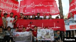 People hold banners during a sit-in in solidarity with the people of Aleppo in Idlib, Syria, May 4, 2016. The banner reads: "Oh, Aleppo, your victory is promised no matter how many crowds they bring to you."