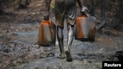 A man carries oil canisters at an illegal refinery site in Nigeria's oil state of Bayelsa in this November 27, 2012, file photo.