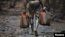 FILE - A man carries oil canisters at an illegal refinery site in Nigeria's oil state of Bayelsa, Nov. 27, 2012.