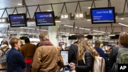 People wait to check in to a flight to Chicago at the United Airlines counter in the main terminal of Brussels International Airport in Brussels, March 12, 2020. 