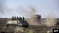 An Israeli Armored Personnel Carrier (APC) and Merkava tanks maneuver during a drill in the Israeli annexed Golan Heights near the border with Syria on May 6, 2013.