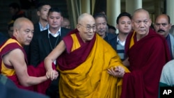 The Dalai Lama, in yellow robe, is helped by attending monks as he leaves after a religious talk at the Tsuglakhang temple in Dharmsala, India, March 14, 2017.