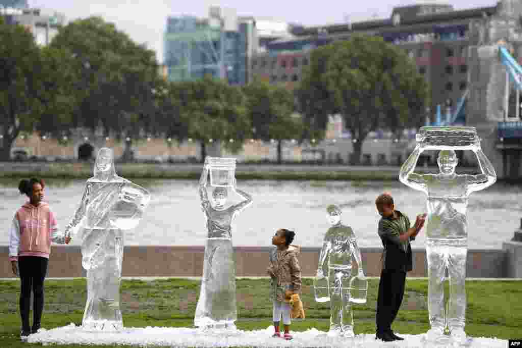 Deca obilaze ledene skulpture koje prikazuju kako ljudi prikupljaju čistu vodu. Eksponat je finansirala dobrotvorna organizacije WaterAid u Londonu. 15. avgust, 2021 ( Foto: Danijel Leal-Olivas / AFP )