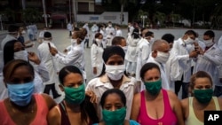 A doctor, at center wearing white, from a brigade of health professionals who volunteered to travel to South Africa to assist local authorities with an upsurge of coronavirus cases, takes a photo with her relatives during the farewell in Havana, Cuba, Apr