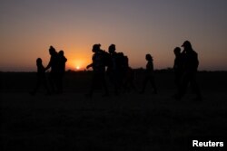 Porodice migranata iz Hondurasa i Salvadora koračaju prema graničnom zidu nakon što su splavom u Penitasu u Texasu iz Meksika prešle rijeku Rio Grande.