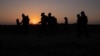 FILE - The sun rises as asylum-seeking migrant families from Honduras and El Salvador walk toward the border wall after crossing the Rio Grande into the United States from Mexico on a raft in Penitas, Texas, on March 26, 2021. 