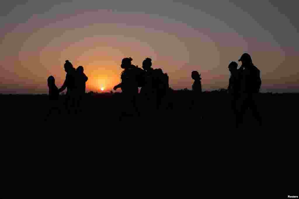 The sun rises as asylum-seeking migrant families from Honduras and El Salvador walk towards the border wall after crossing the Rio Grande River into the United States from Mexico on a raft, in Penitas, Texas.