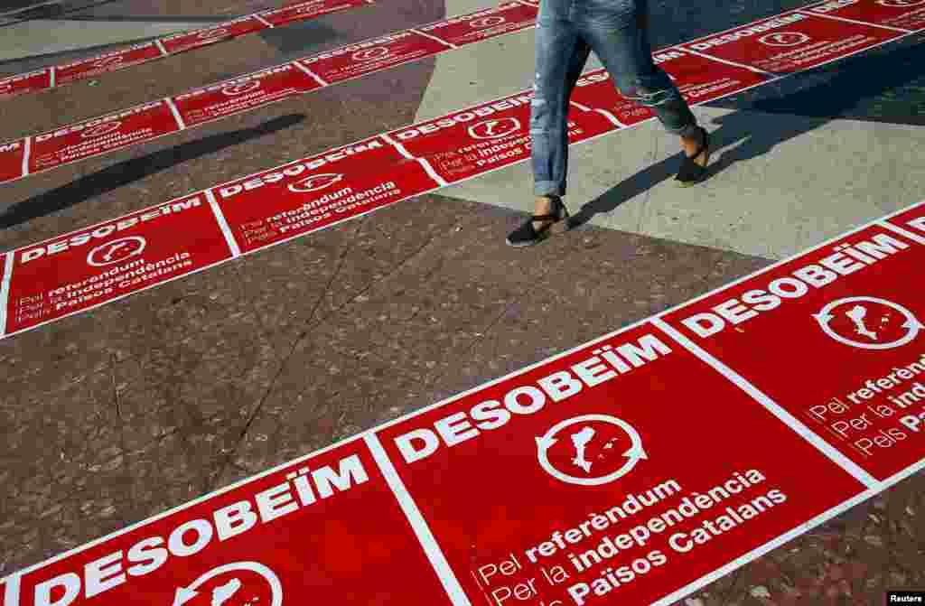 A woman walks past "Disobey" banners during a Catalan pro-independence protest at Catalunya square in Barcelona. 