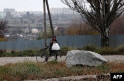 A local resident pushes a bike on a street in Stepnogirsk, a village on the east bank of the Dnipro River, on Nov. 9, 2022, amid the Russian invasion of Ukraine.