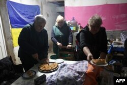 Local residents prepare food in a shelter in the basement of a residential building in Stepnogirsk on the east bank of the Dnipro River, south of Zaporizhzhia, on Nov. 9, 2022, during the Russian invasion of Ukraine.