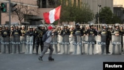 Un hombre sostiene una bandera nacional frente a los policías durante una protesta contra el gobierno del presidente de Perú, Pedro Castillo, en Lima, la capital, el 5 de noviembre de 2022.