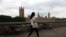 FILE - A pedestrian walks opposite The Palace of Westminster, the official name of Britain's Houses of Parliament, home to the House of Lords and the House of Commons, in London on July 21, 2022.