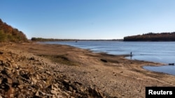 FILE - People walk along the banks of the Mississippi River, which has seen record-low water levels, in Grand Tower, Illinois, Nov. 2, 2022.