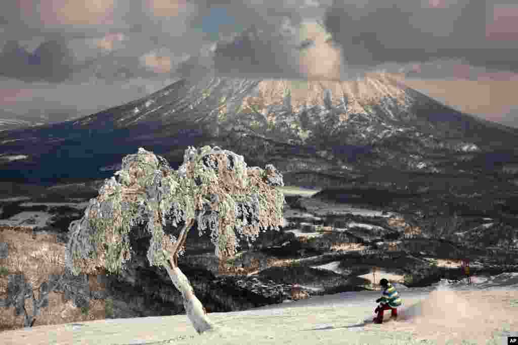 A man snowboards down a slope overlooking Mount Yotei at a ski resort in Niseko, Hokkaido, Japan.