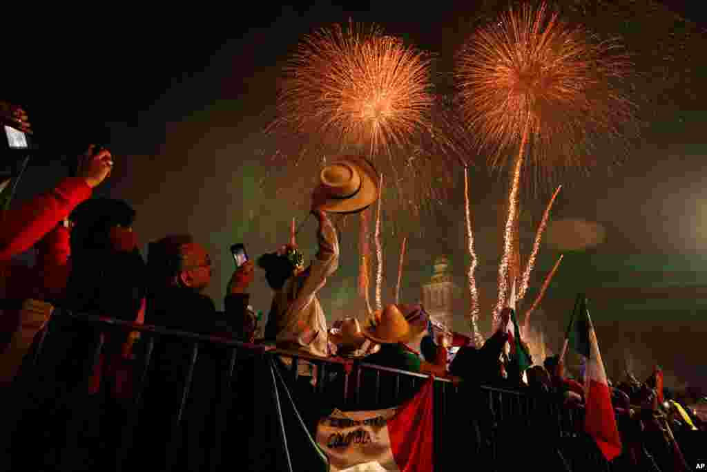 Revelers celebrate as fireworks explode over the Metropolitan Cathedral, marking the start of Independence Day celebrations in Mexico City, Sept. 15, 2019.