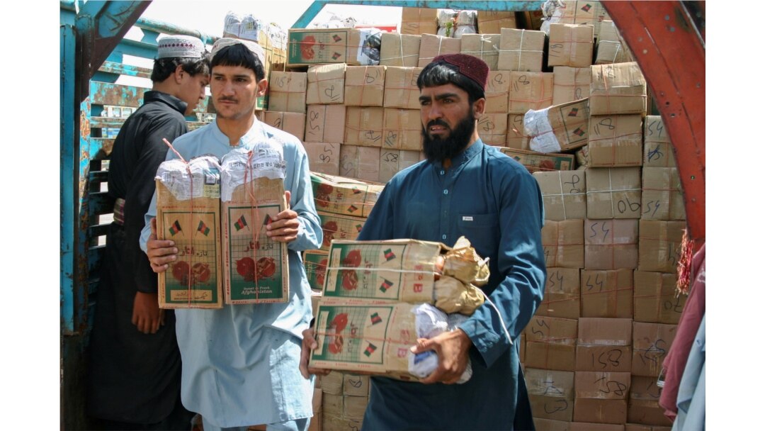 Para pekerja membongkar truk bermuatan kotak buah delima dari Afghanistan, di titik persimpangan 'Gerbang Persahabatan', di Chaman, Pakistan, kota perbatasan Pakistan-Afghanistan, 7 September 2021. (REUTERS/Saeed Ali Achakzai/File Foto)