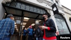 Seorang pejalan kaki mengenakan masker di luar Toko Apple saat wabah virus corona (COVID-19) di Pasadena, California, 14 Maret 2020. (Foto: Reuters)