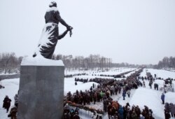 FILE - People walk in snowfall to the Motherland monument to put flowers at the Piskaryovskoye Cemetery where most of the Leningrad Siege victims were buried during World War II, in St.Petersburg, Russia, Jan. 26, 2019.