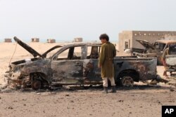A Yemeni southern separatist fighter inspects the wreckage of government forces vehicles destroyed by UAE airstrikes near Aden, Aug. 30, 2019.