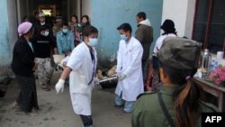 Para petugas medis di rumah sakit Laiza mengangkat seorang pria yang terluka dengan menggunakan tandu (14/1). Pasukan militer Burma melancarkan serangan artileri di kota Laiza yang digunakan sebagai markas besar pemberontak Kachin, Senin dini hari.