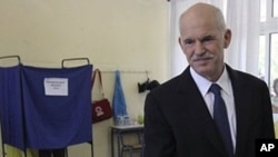 Greek Prime Minister George Papandreou receives an envelope to vote during the municipal and regional elections in Athens, 7 Nov. 2010.