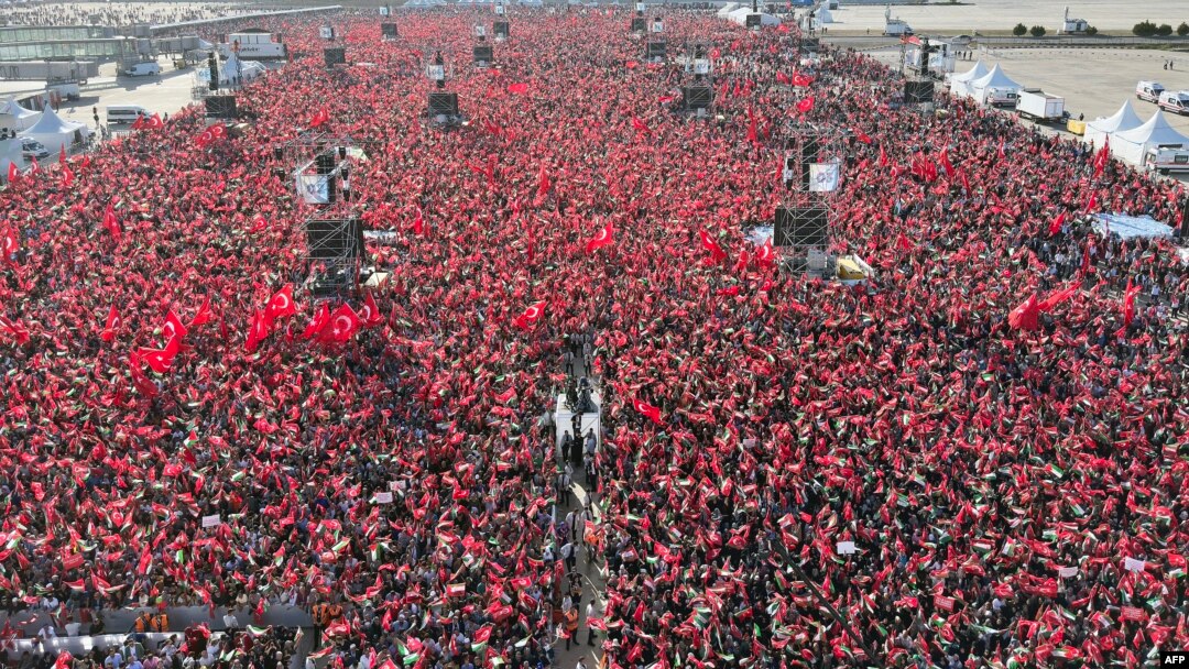 Ljudi mašu turskim i palestinskim zastavama dok turski predsjednik govori tokom skupa koji je organizovala stranka AKP u znak solidarnosti s Palestincima u Gazi, u Istanbulu 28. oktobra 2023.