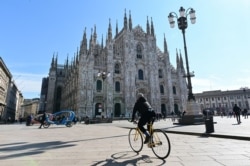 A biker rides past the Duomo di Milano on Piazza del Duomo in central Milan on March 8, 2020, after millions of people were placed under forced quarantine in northern Italy.