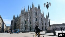 A biker rides past the Duomo di Milano on Piazza del Duomo in central Milan on March 8, 2020.